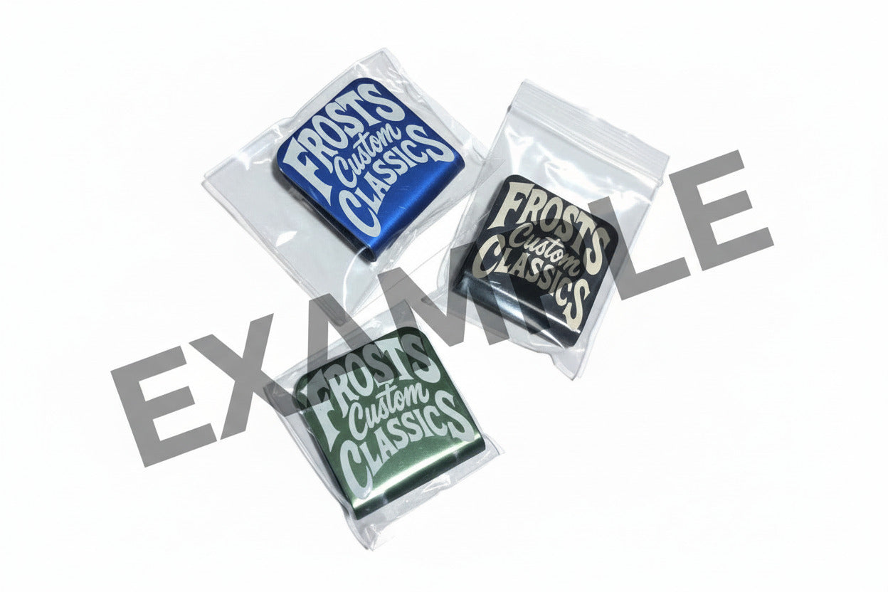 EXAMPLES - Blue Black and Green colored hat clips with Frosts Custom Classics logo engraved on them, set on a white background.