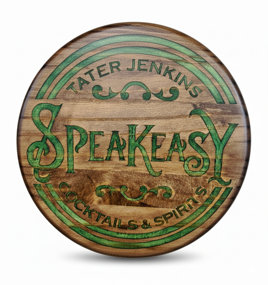 Wooden circular sign with 'Tater Jenkins Speakeasy Cocktails & Spirits' engraved in green text on a white background