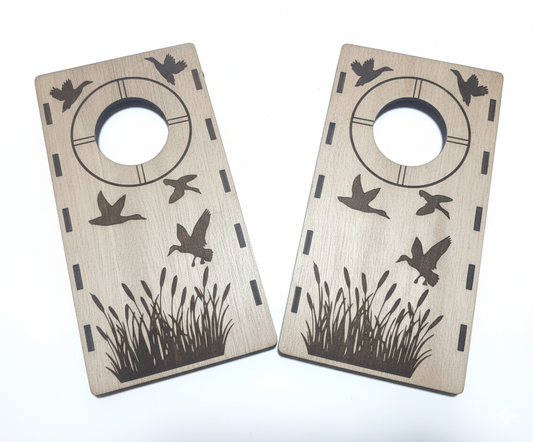 Two wooden mini cornhole boards with bird and grass designs on a white background