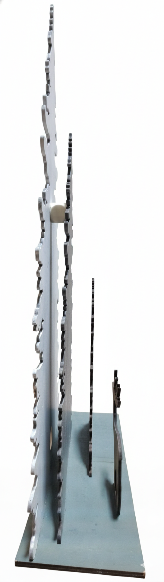 side view of tall trees decoration showing thin wood of 4 pieces on a base, pictured on a white background